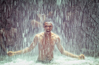 Man under a waterfall bathing in the river