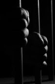 hands holding jail bars black and white pic