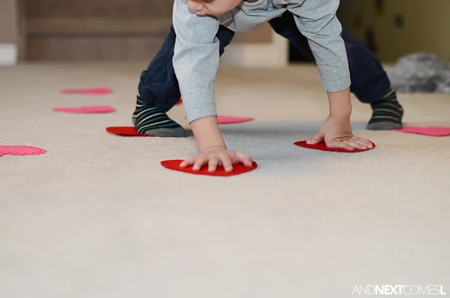 Preschool child playing twister like game with felt hearts as part of a Valentine's Day gross motor activity