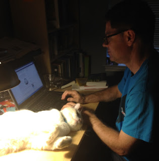 David working on his blog with Charlie the Cat lounging nearby