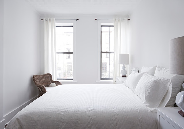 Simple, clean white bedroom with a wicker armchair