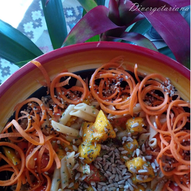 Ensalada de pasta y mango con zanahoria, pipas y sésamo junto a una planta