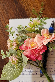 A bouquet of pink flowers on top of a notebook with writing.