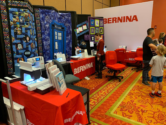 Sewing machines and science-fiction-themed quilts line the back wall of the Bernina Center in the SoonerCon Exhibition Hall.