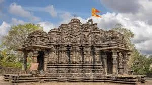 An ancient temple with intricate carvings and towering spires. The stone structure is adorned with detailed sculptures, and the temple grounds are surrounded by greenery.