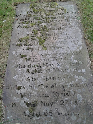 A laid down flat, moss covered gravestone, transcription in the text adjacent.