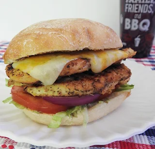 Chicken sandwiches with lettuce tomato onion and cheese on a white plate