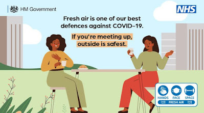 If meeting up, outdoors is safest UK Gov drawing of 2 ladies sitting outside drinking wine and chatting