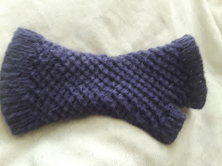 a purple fingerless mitten with a spiralling star texture along the cuff and hand