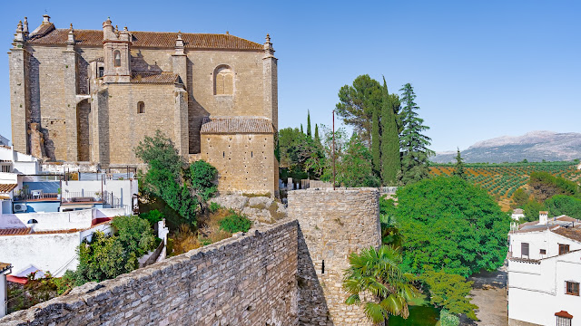 Antiguas murallas de piedra con bonita iglesia medieval y el pueblo tras ella.