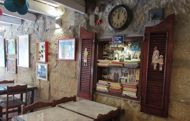 mesas de testaurante quadros na parede e uma prateleira com livros