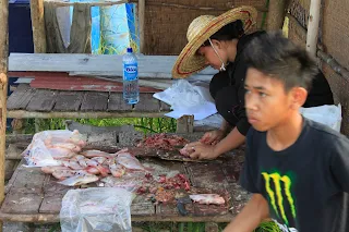 Gambar seorang wanita sedang menyiang ikan-ikan yang ditempah pelanggan.