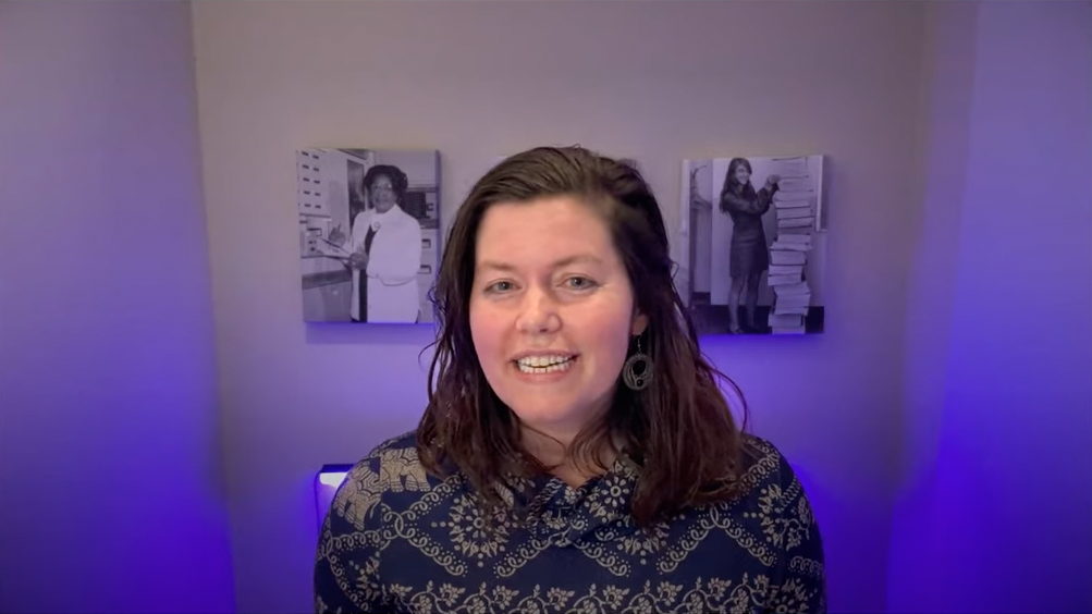 Photo of Pamela in front of a purple-hued wall