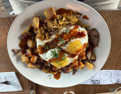 A plate of Smoked Brisket Hash & Eggs with a runny fried egg on top of a plate of brisket and hashbrowns.