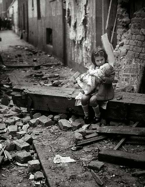 Маленькая девочка с куклой, сидящая в руинах ее разбомбленного дома, Лондон, 1940 г.