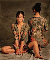 Two Japanese women, seated, both have traditional full body tatoos