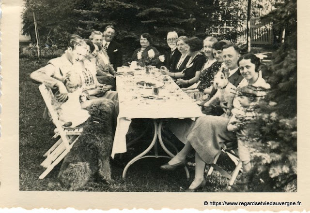 Photo noir et blanc ancienne :  toute la  famille réunie autour de la table même le chien