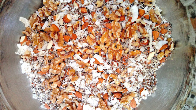 a large stainless steel bowl full of mixed nuts, seeds, and coconut for Grain Free Granola