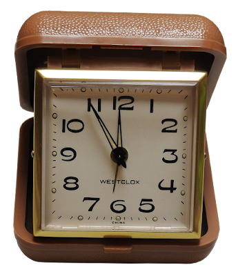 A vintage fold-up Westclox travel alarm clock in brown case.