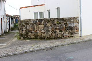 muro de piedra que hace curva de una altura de 1,50 por un ancho de 0,40 que separa de la zona del jardin a la calle