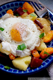A meatless main dish salad recipe composed of roasted root vegetables like beets, carrots, and potatoes over tender bok choy, topped with a fried egg.