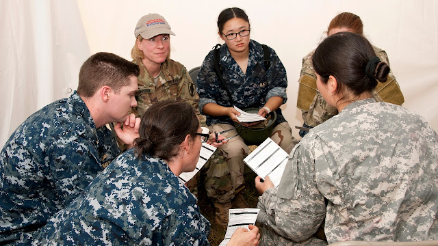 A group of people in military fatigues sit in a circle