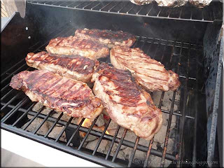 New York strip steaks on charcoal grill