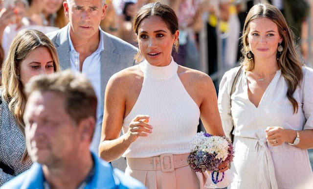 Meghan Markle wore a new ivory Kylin sweater by Anine Bing, and belted pleated wool-blend twill wide-leg pants by Brandon Maxwell