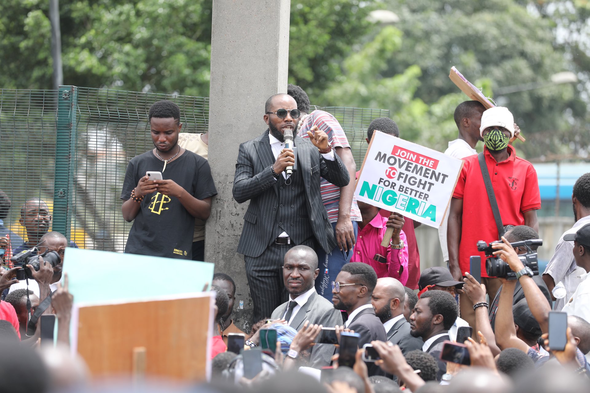 Human Rights Lawyer, Inibehe Effiong, with protesters at the Gani Fawehinmi Freedom Park, Ojota, Lagos, on Friday 2 August, 2024. In the photo, a protester lifts high a banner which says "join the movement to fight for a better Nigeria"