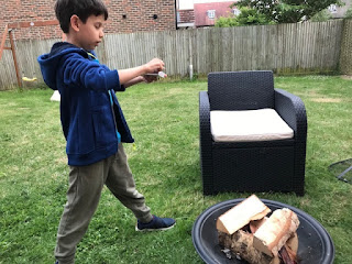 Child lighting a fire pit int he garden