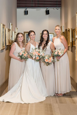 bride with bridesmaids in light colored dresses holding white and pink bouquets