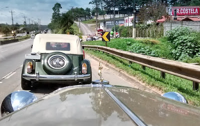 Uma mão no volante e outra para acionar a máquina fotográfica, no acostamento da estrada.