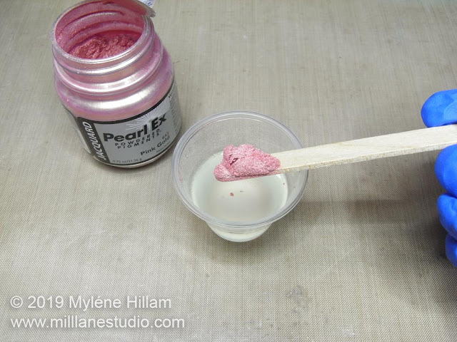 Placing a rounded scoop of Pink Gold Pearl Ex powder into Part A of the resin.