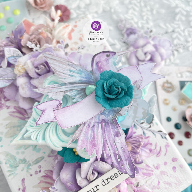 Mixed media canvas featuring a hummingbird and paper flowers from the Prima Marketing The 3 Girls Tale collections Lost in Wonderland, Postcards from Paradise and Aquarelle Dreams.