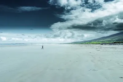 Pessoa solitária caminhando na areia da praia. #PraCegoVer