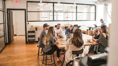 Des collaborateurs réunis autour d’une table dans un espace de coworking moderne, illustrant un management collaboratif adapté au travail hybride et aux modèles de leadership distribués en 2025.