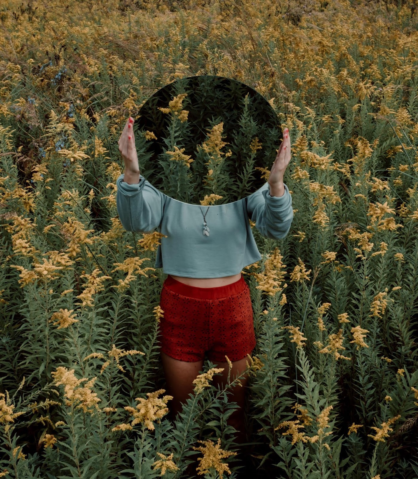 donna con specchio in mano in un campo di fiori