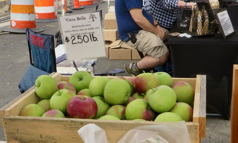 Bin of green, red-blushed apples with a sign that reads, "Vista Bella, moderately juicy with a flavor that is mildly tart, good for fresh eating, $250 lb."