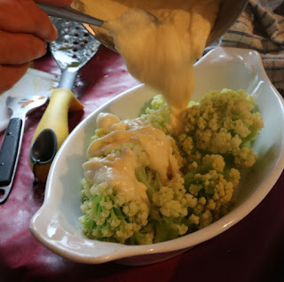 Cheese sauce being poured onto cauliflower
