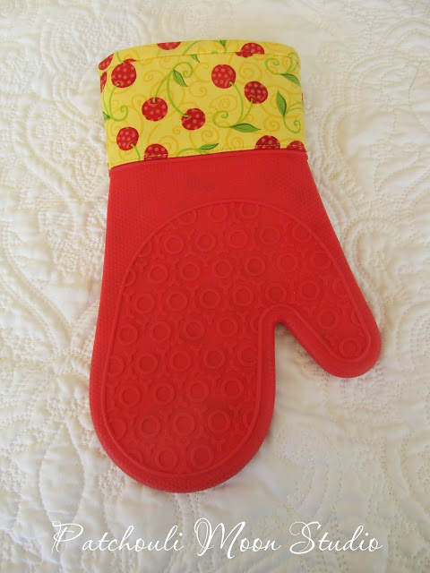 Oven mitt in yellow and red cherry fabric with red silicone.