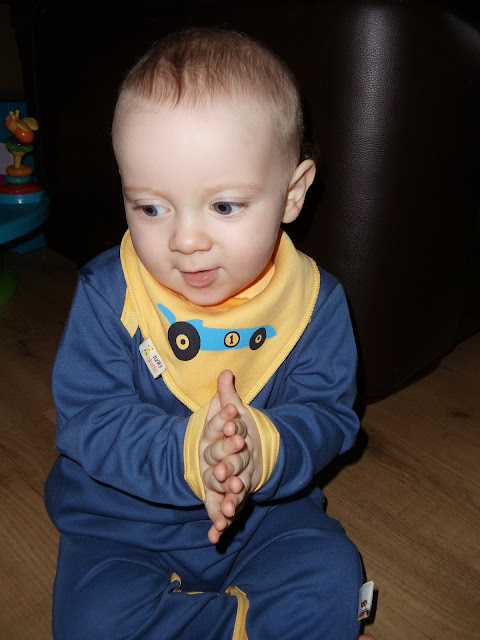 A baby boy sitting up clapping his hands