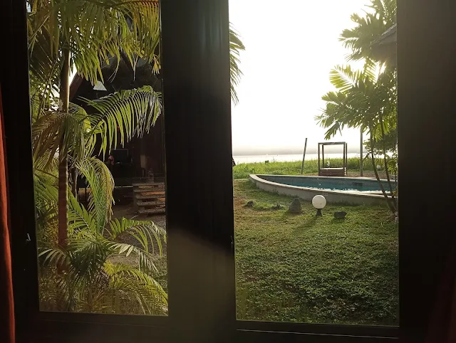 "View of the jacuzzie and swimming pool of Houttuyn Wellness River Resort in front of the Suriname River from the Midi Cabana's window view"