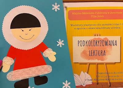 Po lewej stronie zdjęcia widoczna praca plastyczna. Na niebieskiej kartce czarnowłosy Eskimos w czerwonym kubraku i czarnych butach. Dookoła Eskimosa przyklejone białe śnieżynki. Po prawej stronie żółto-pomarańczowy plakat, promujący zajęcia z cyku PodKOLORyzowana lektura.