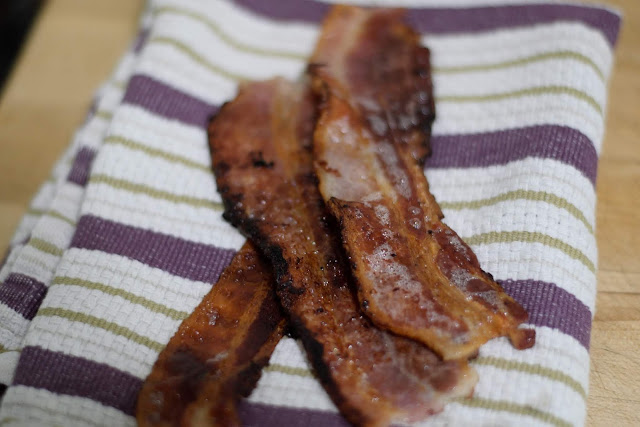 The three pieces of bacon, fully cooked, on a towel.