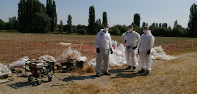 werkmannen die stukken asbest van het terrein rapen