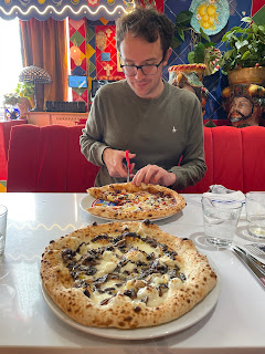 John cutting his pizza in to slices, with my pizza in the foreground.