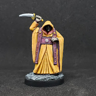 Cultist miniature in yellow robe with upraised curved dagger