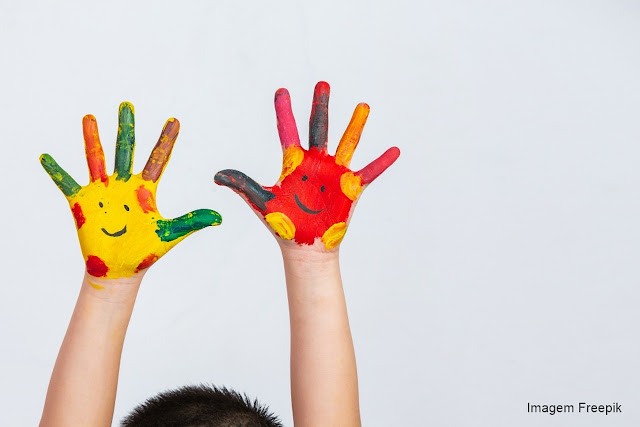 Criança com autismo com as palmas das mãos pintadas.