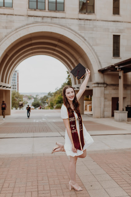 Madalyn holding graduation cap on the Texas State University campus.