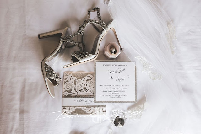 wedding detail flatlay with white invitation and silver bridal heels